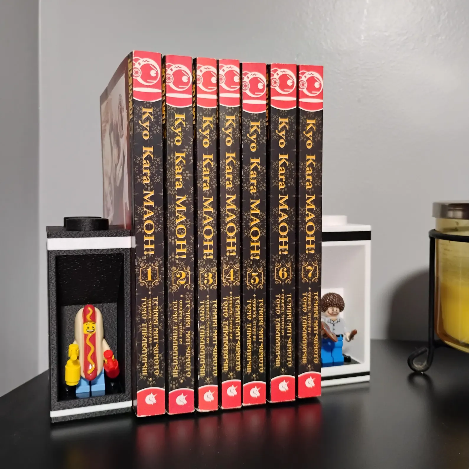 LEGO® minifigure bookends securing fantasy hardcover novels. Each end features an inset figure mount and modern black-and-white design.