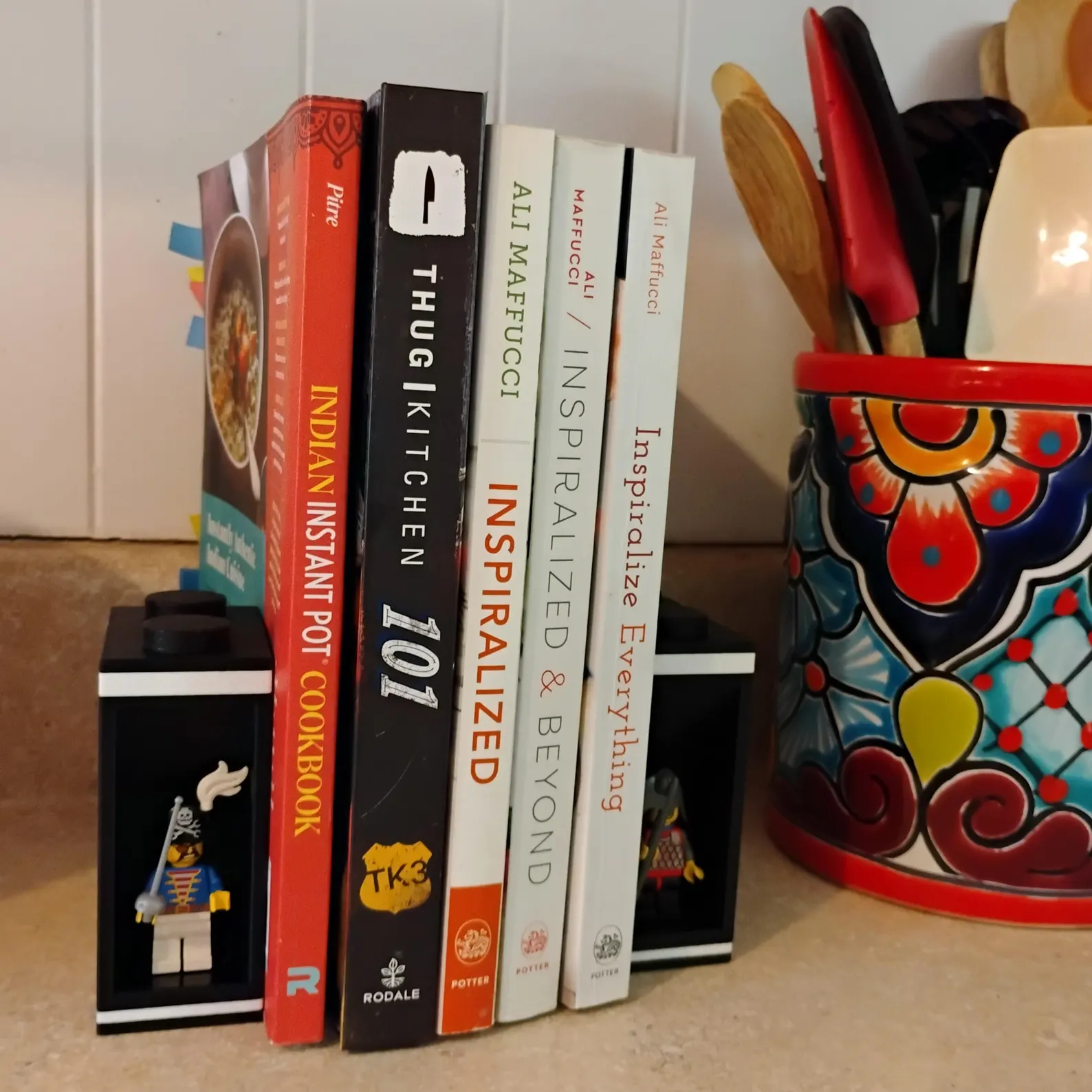 LEGO® bookends holding cookbooks beside a kitchen utensil holder. Stylish and functional design doubles as minifigure display.