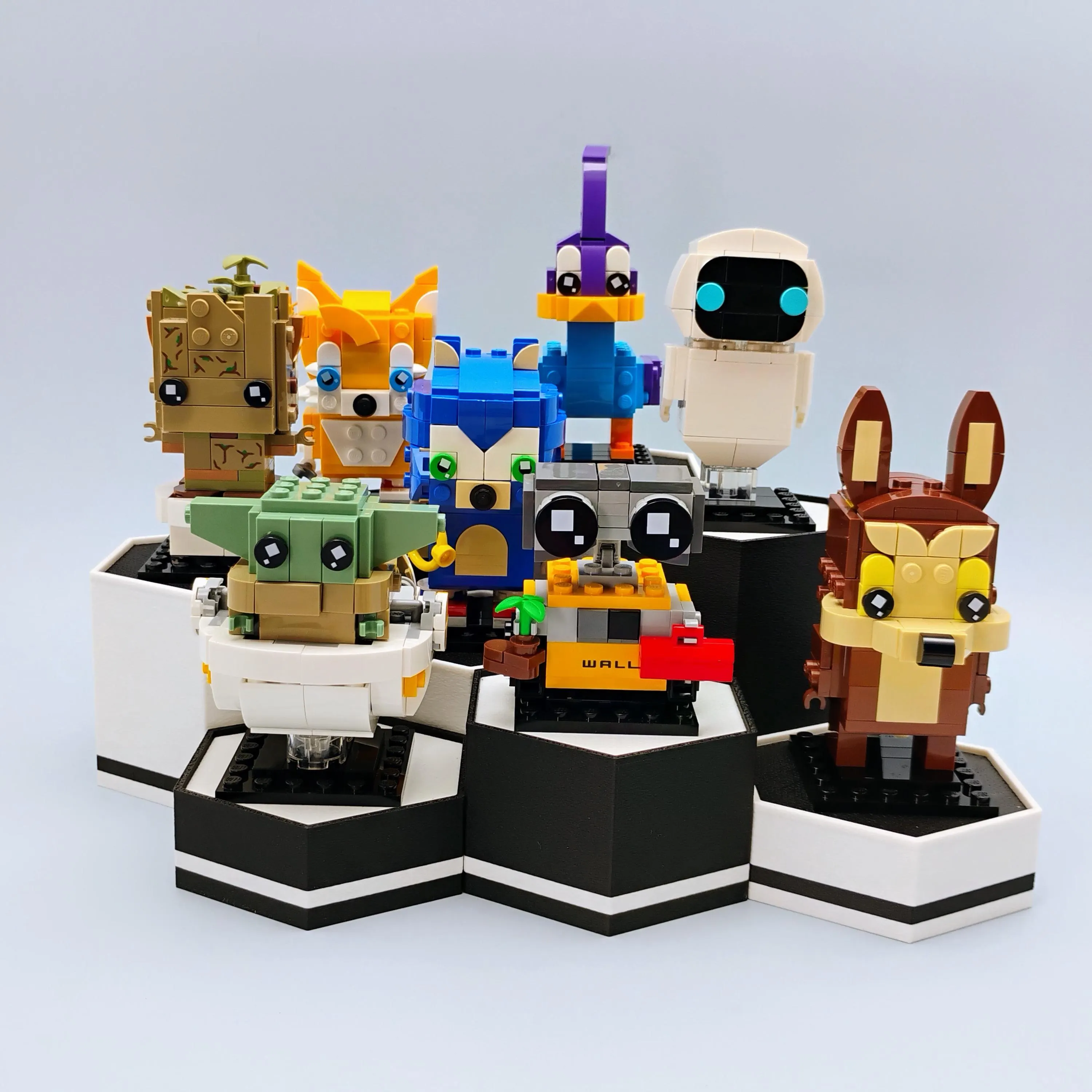 Hexagonal display stands showcasing LEGO® BrickHeadz on matte black and white bases arranged in a tiered set.