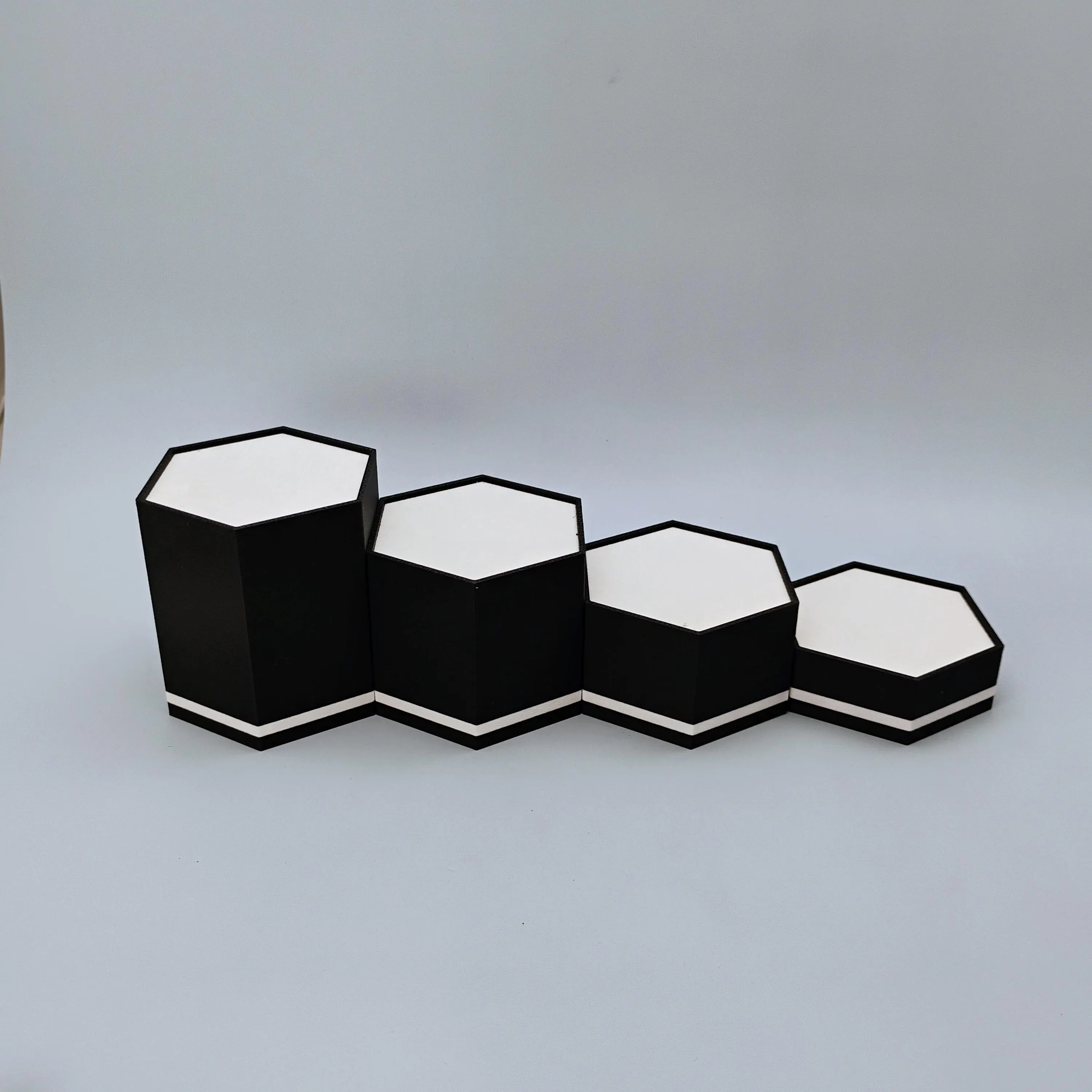 Empty matte black hexagonal display stands shown in single line layout for collectors and desk displays.