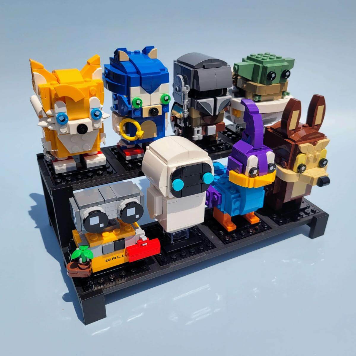 Angled view of a two tier LEGO BrickHeadz display stand, loaded with eight collectible characters. The display is four slots wide and two rows tall, ideal for compact setups. Organize and showcase your BrickHeadz collection with style and visibility. Matte black frame is lightweight, durable, and easy to assemble. Stand only; LEGO figures not included.
