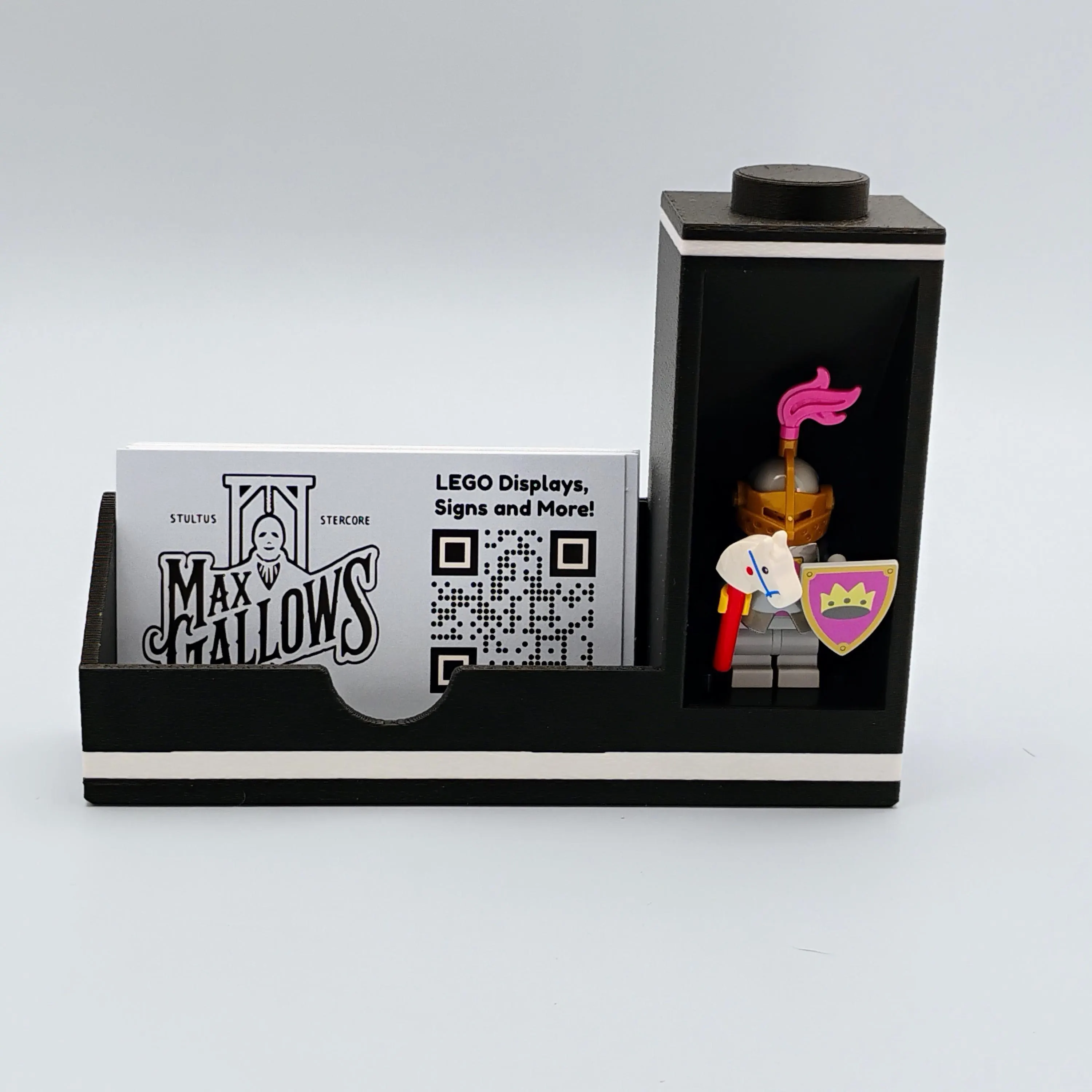 Black matte bookend-style minifigure display stand with two LEGO® minifigures and a business card. Sleek modular display for workspaces.