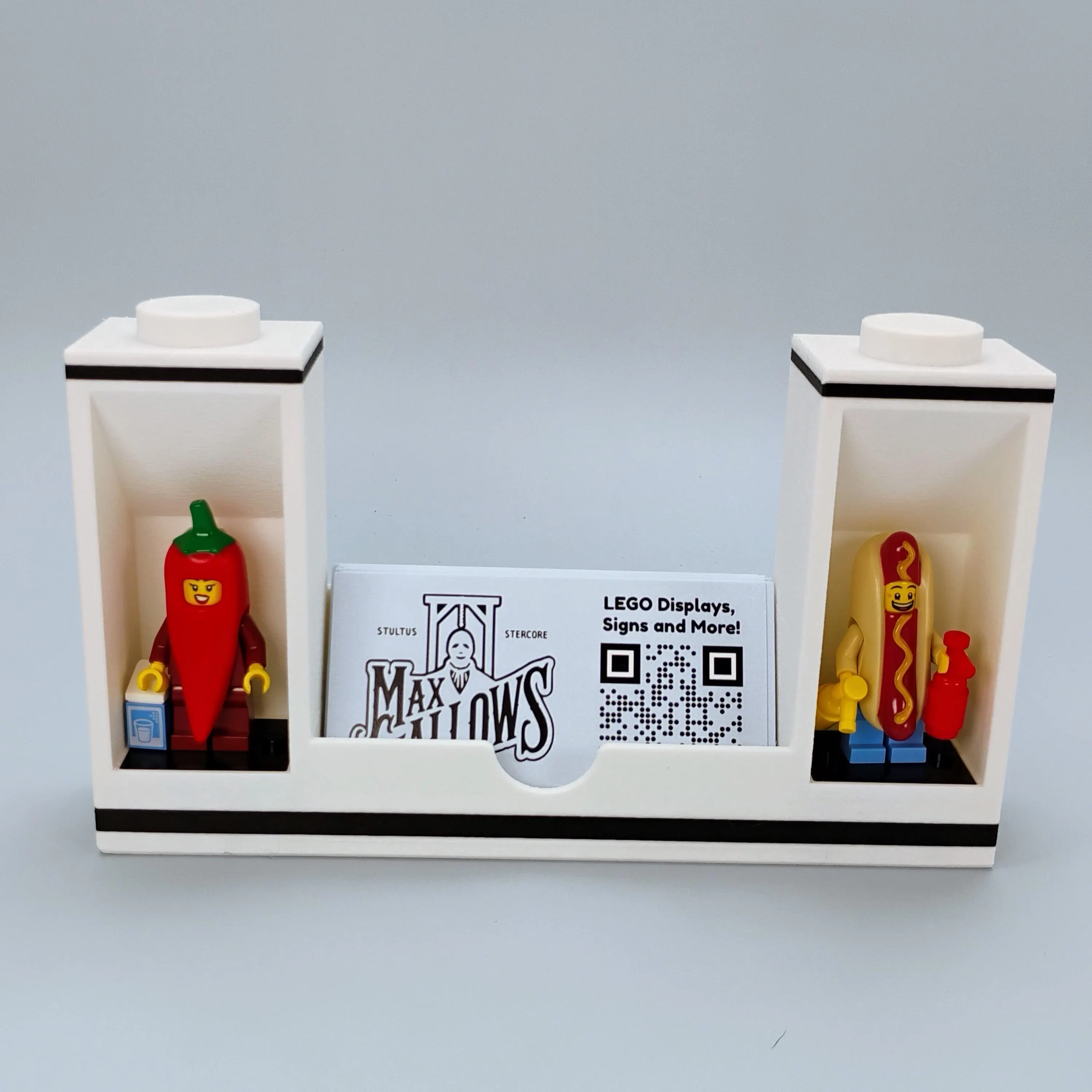 White modular LEGO® minifigure display stand bookend used as a business card holder, compatible with modular display modules.