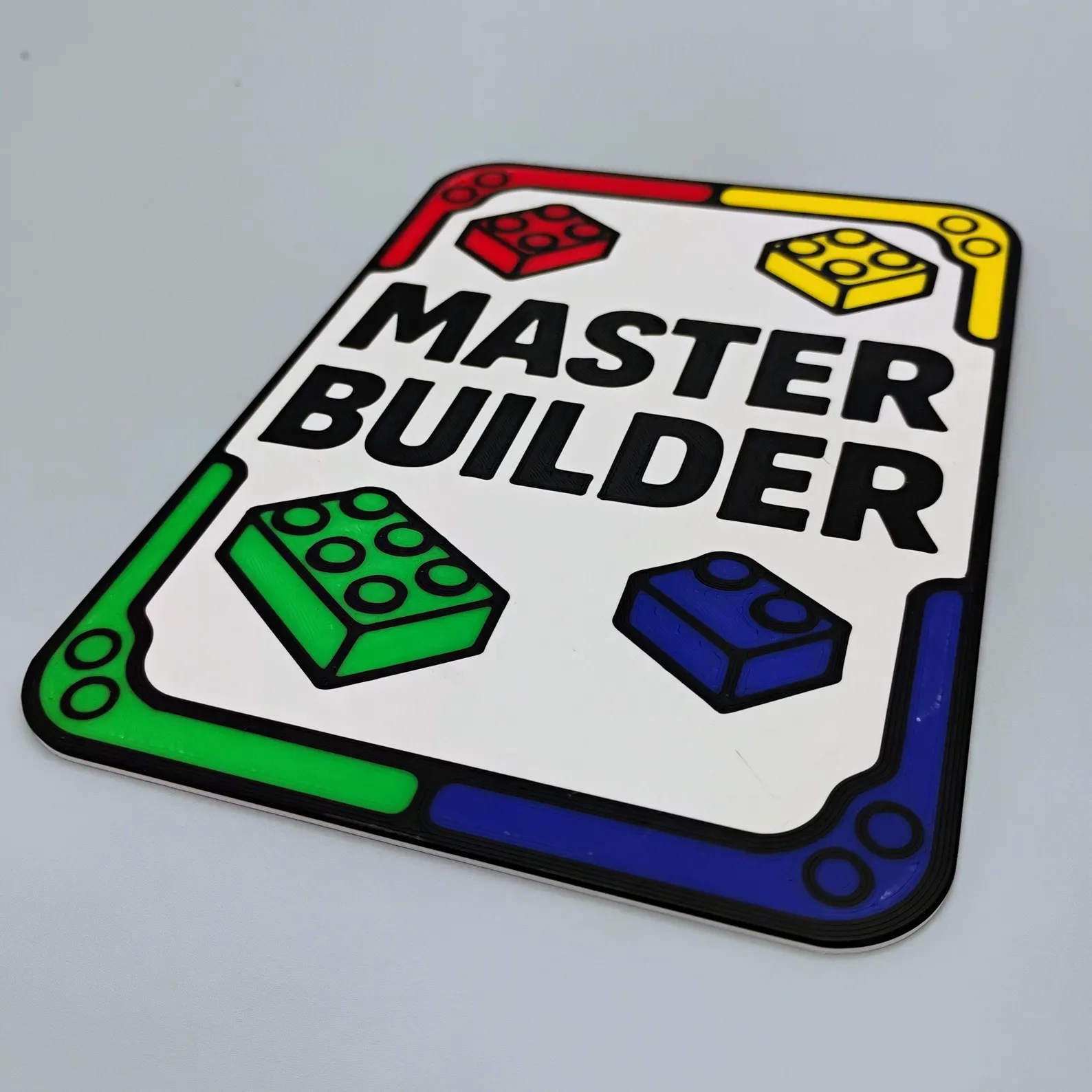 Master Builder sign with bold red, yellow, green, and blue brick graphics around the border and Master Builder text centered like a badge.