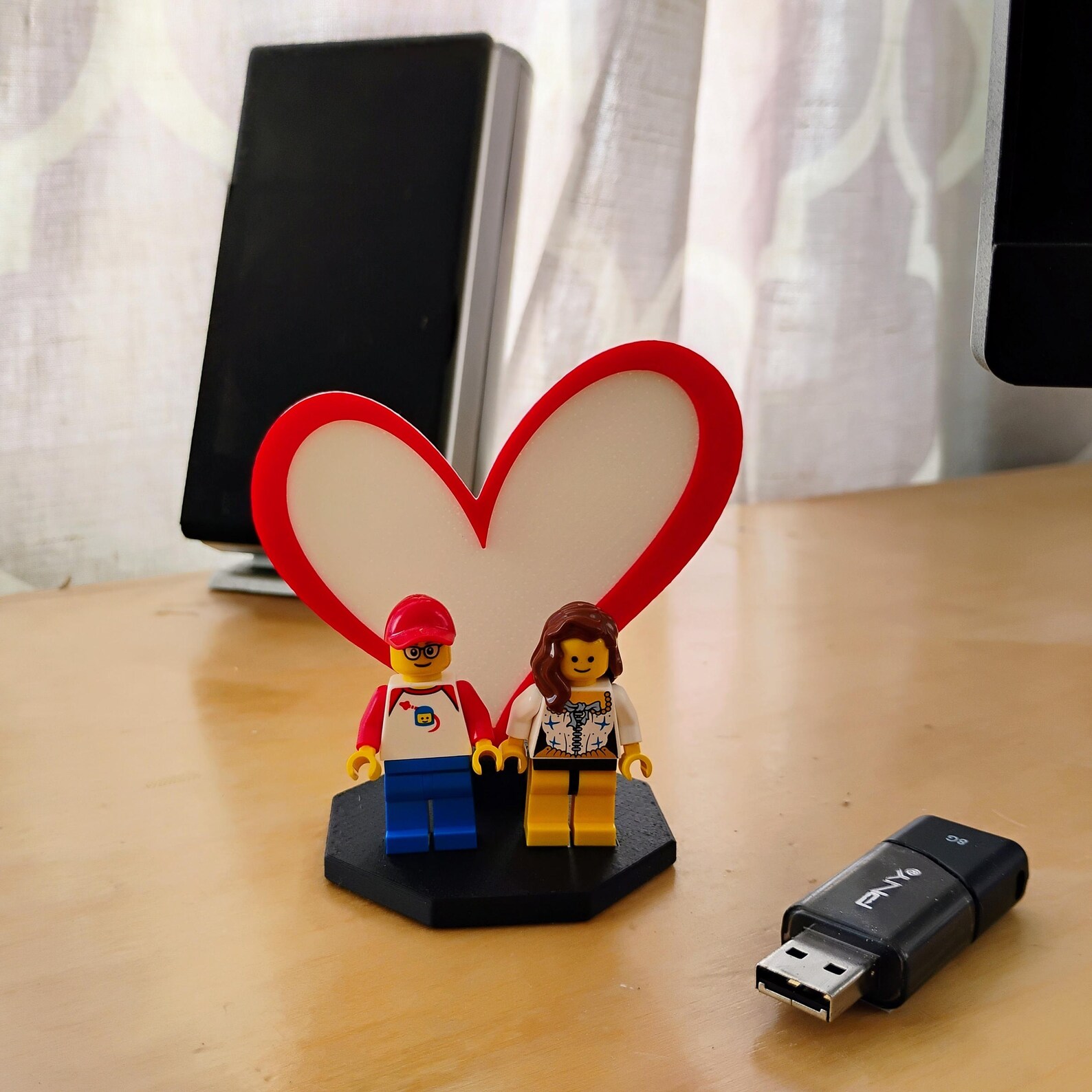 Heart Display for LEGO® minifigures shown on a desk with a USB drive for size reference, demonstrating the compact footprint and suitability for desks, shelves, or workspaces.