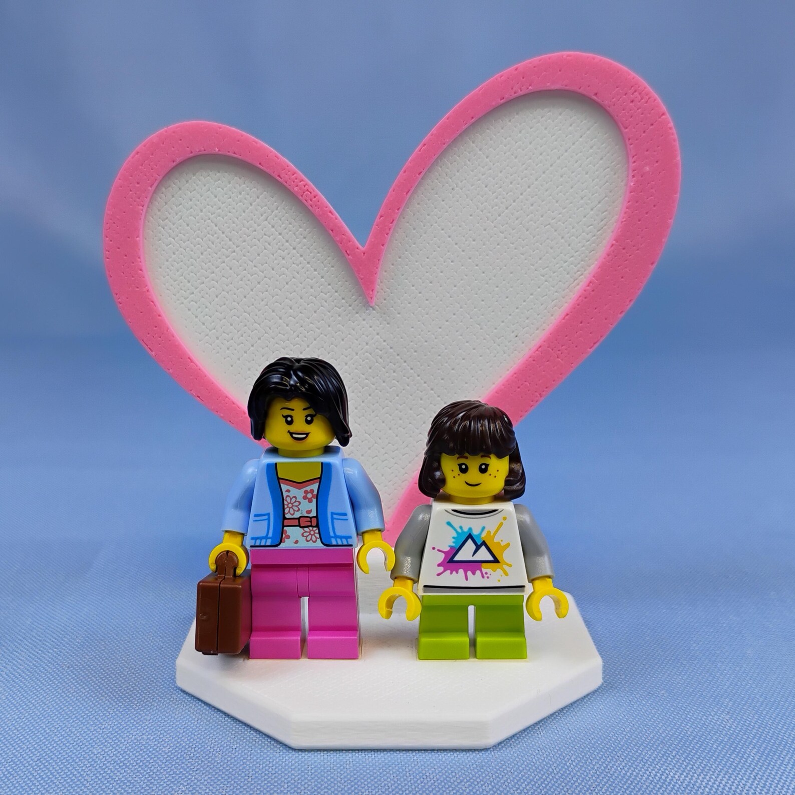 Heart Display for LEGO® minifigures with a white base and raised pink heart outline, holding two minifigures for a softer, playful Valentine gift look.
