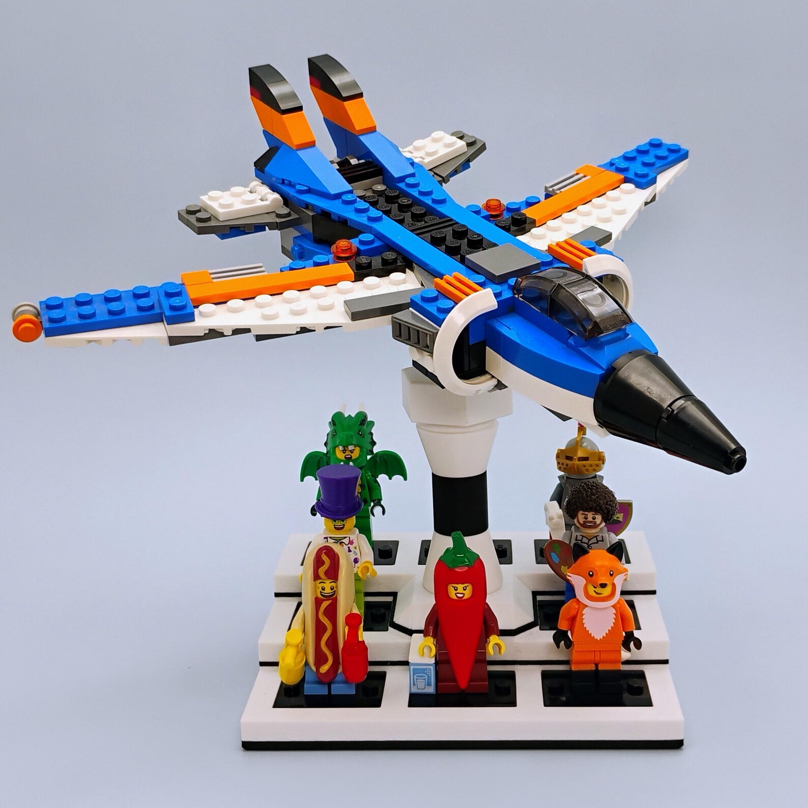 Front view of the minifig platform beneath the mounted ship showing figures organized on modified 3x4-style plates.