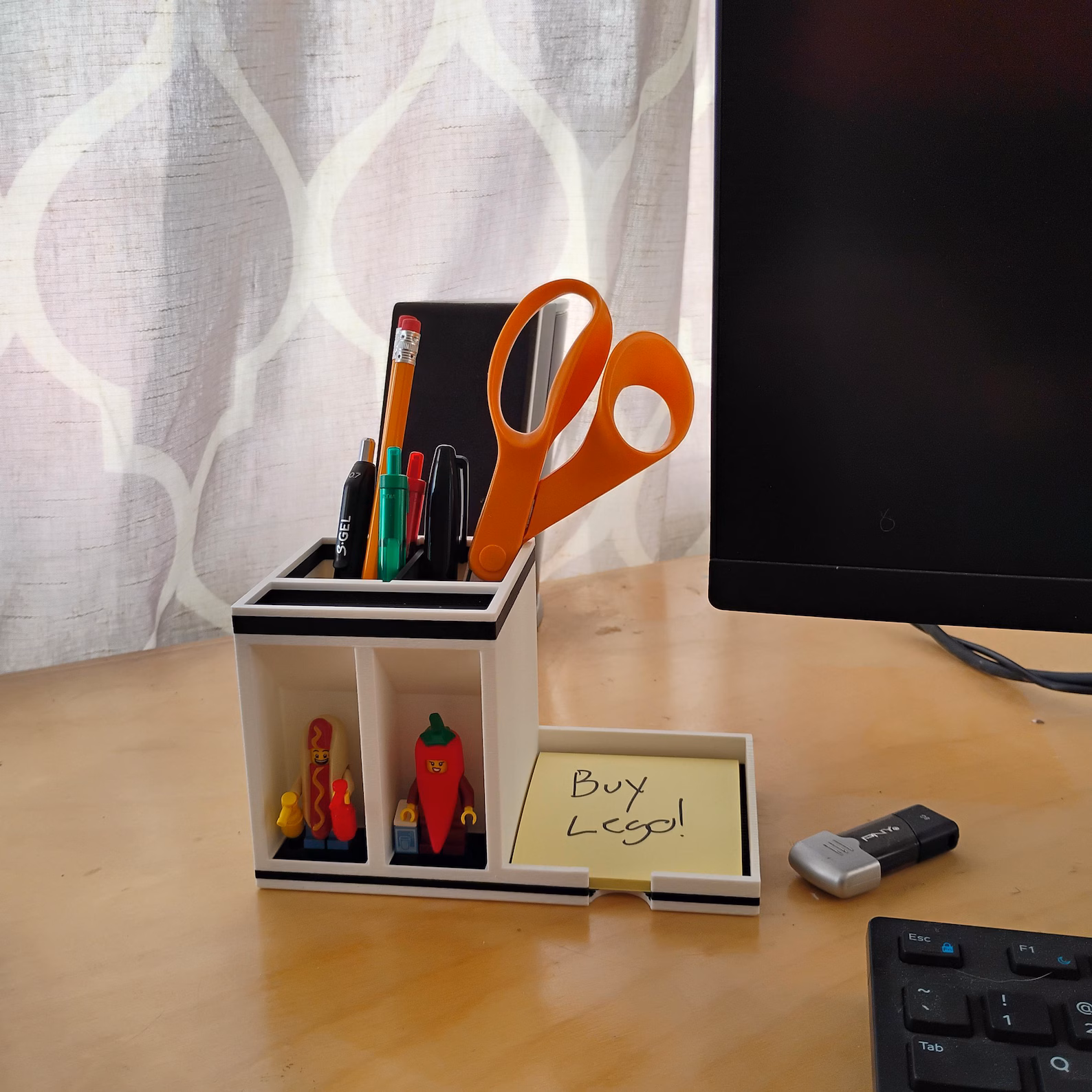 Lifestyle photo of a post-it note holder desk organizer on a home office desk. Shows real-world use with writing tools, sticky notes, and display compartments styled in a working environment.