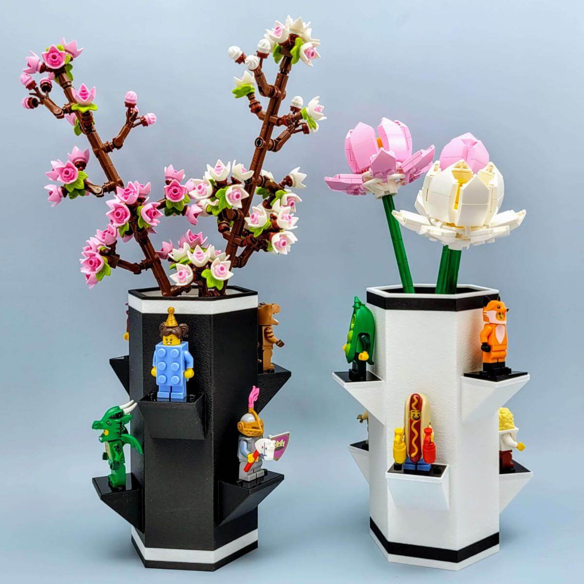 Dual vase photo showing black and white LEGO compatible botanical vases, one filled with LEGO cherry blossoms and the other with LEGO lotus flowers. Minifigures are staged on each side. Shows color and flower options available. Emphasizes modular design and compatibility with various LEGO flower sets.