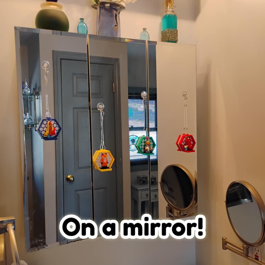 LEGO® minifigure displays hanging on a bathroom mirror and cabinet door using clear line. Renter friendly setup with no drilling.